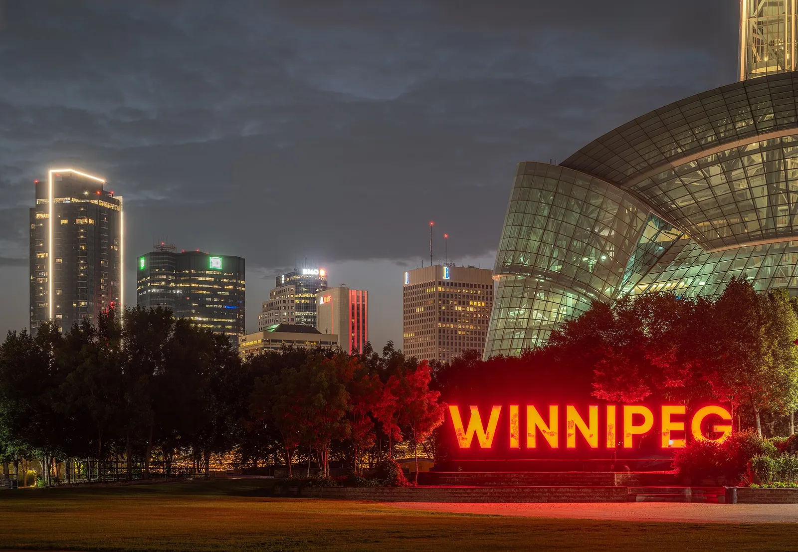 Downtown Winnipeg at dusk from The Forks, with the illuminated WINNIPEG sign