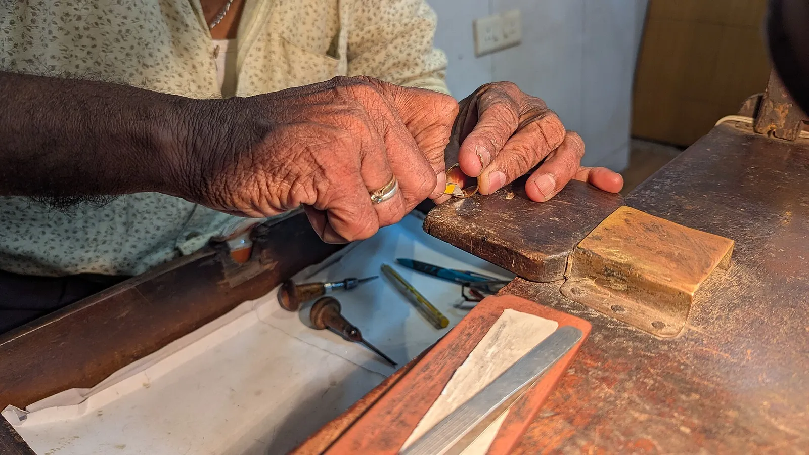 Goldsmith's hands engraving a ring at a workbench