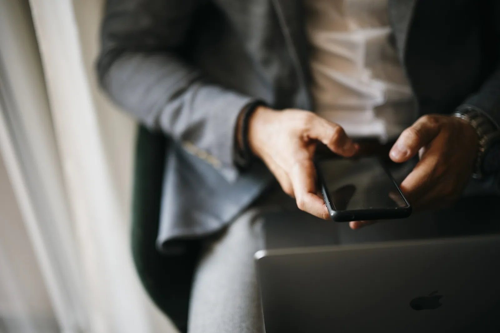 Hands using a smartphone app beside a laptop