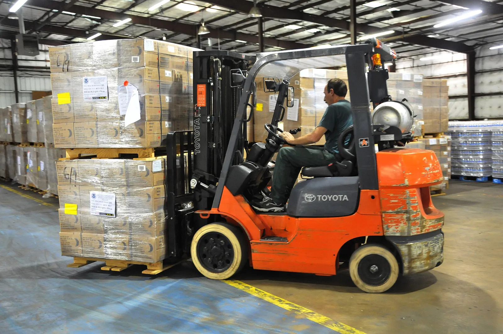 Forklift moving stacked pallets inside a warehouse