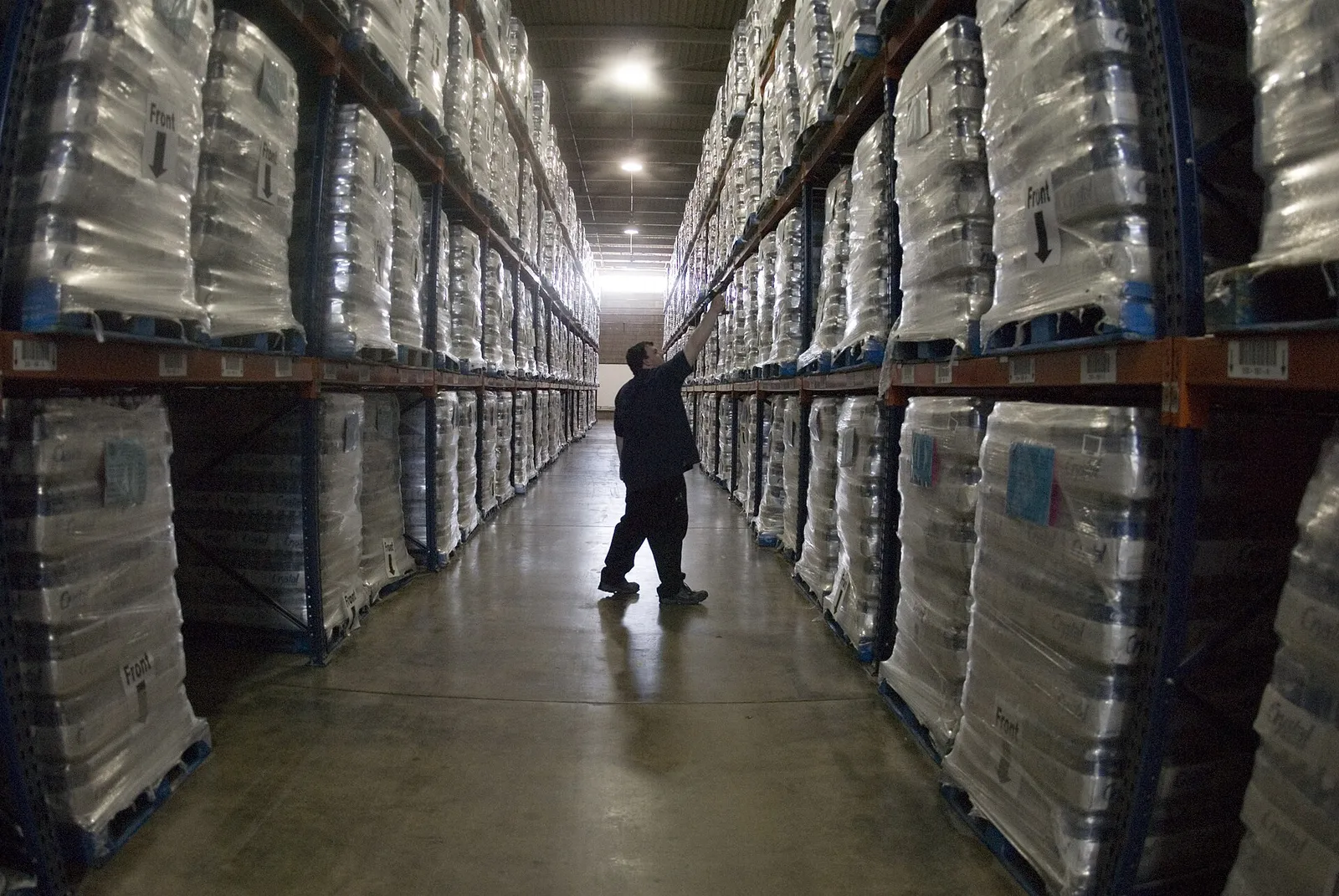 Warehouse worker scanning stock in a racked aisle