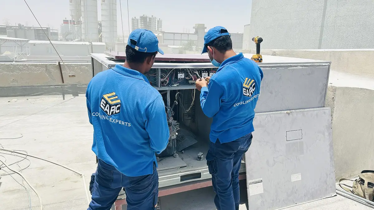 Two technicians servicing a rooftop air-conditioning unit